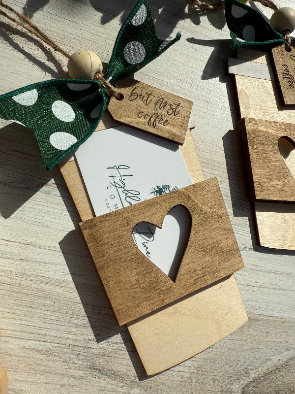 Wooden gift card holder with heart cutout and decorative tag on a wooden surface