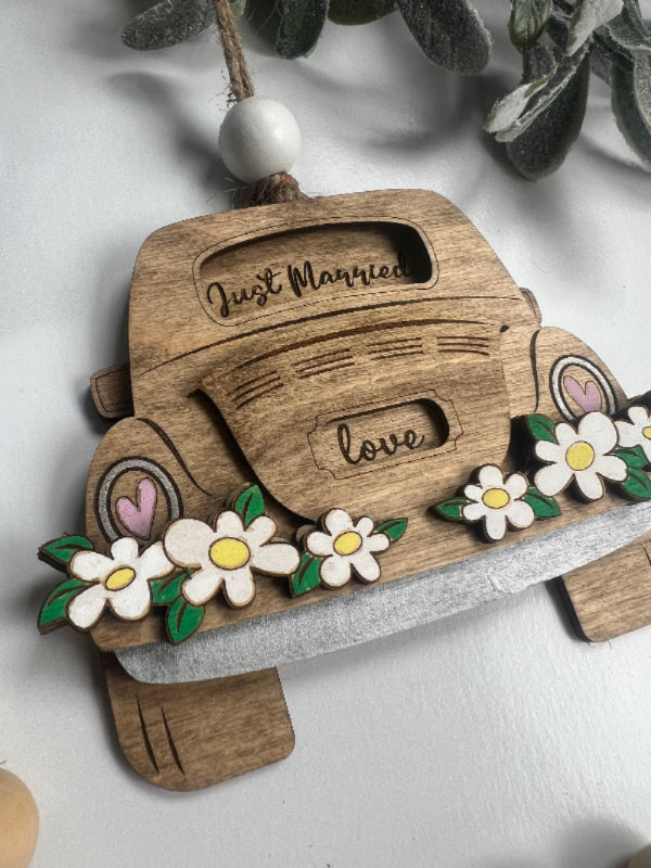 Wooden ornament and gift card holder shaped like a vintage car with floral decorations on a white background