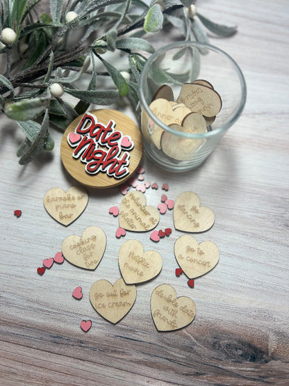 Wooden heart-shaped tokens with date ideas on a wooden surface with a glass container.