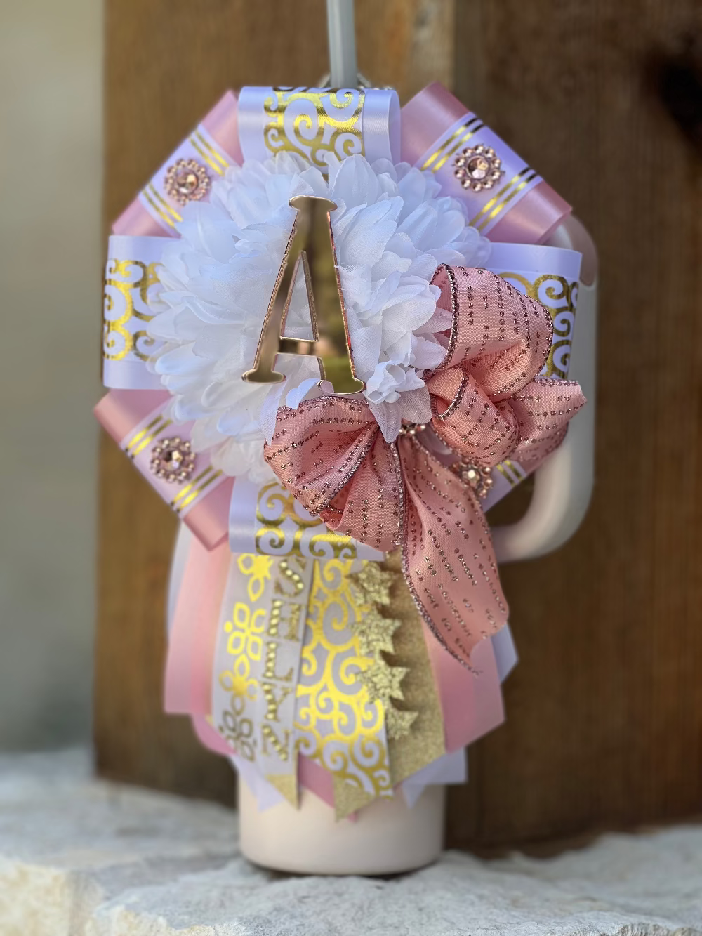 Decorative letter 'A' with ribbons and flowers on a neutral background