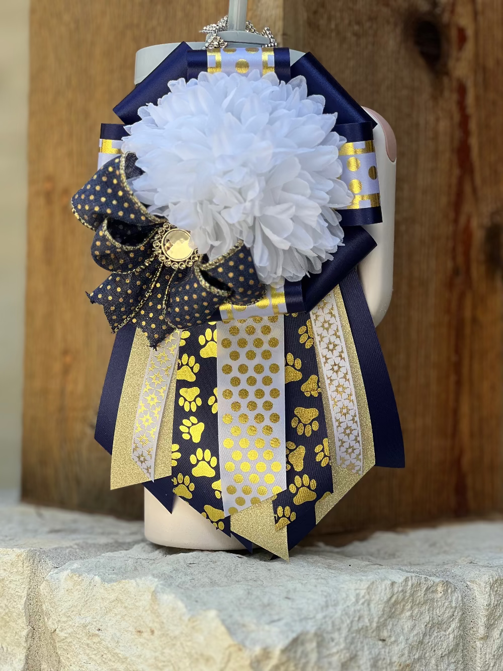 Decorative bow with white flowers, gold and navy patterns on a wooden background