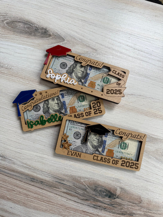 Graduation-themed gift cards with names and class years on a wooden surface