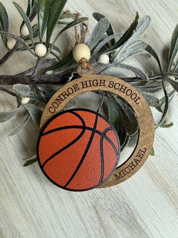 Decorative ornament with basketball design and 'Conroe High School' text, placed on a branch.