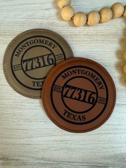Two leather coasters with 'Montgomery 77316 Texas' engraving on a leatherette surface.