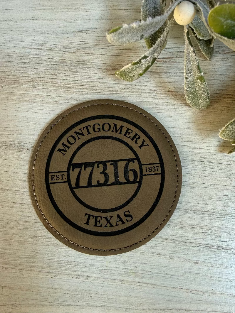 Round leather coaster with 'Montgomery 77316 Texas' engraving on leatherette surface.