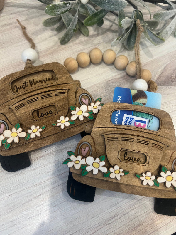 Wooden car-shaped gift card holders with decorative elements on a light wooden surface.