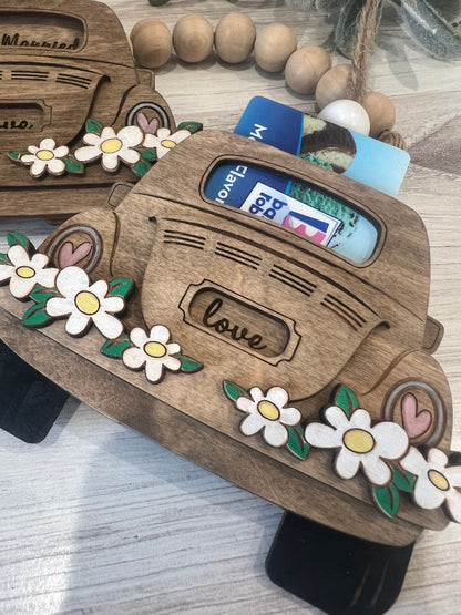 Wooden card holder shaped like a vintage car with floral designs on a wooden surface.