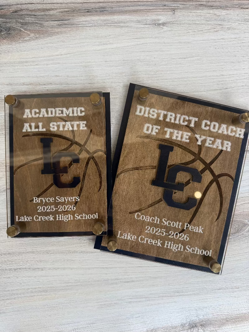 Two wooden plaques with engraved text on a wooden surface