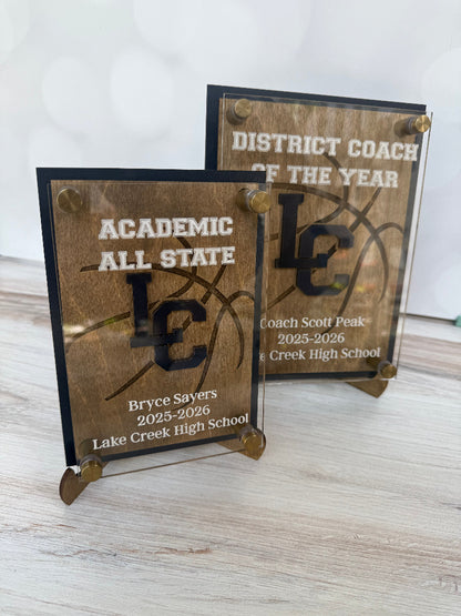 Two wooden plaques with engraved text on a light wooden surface.