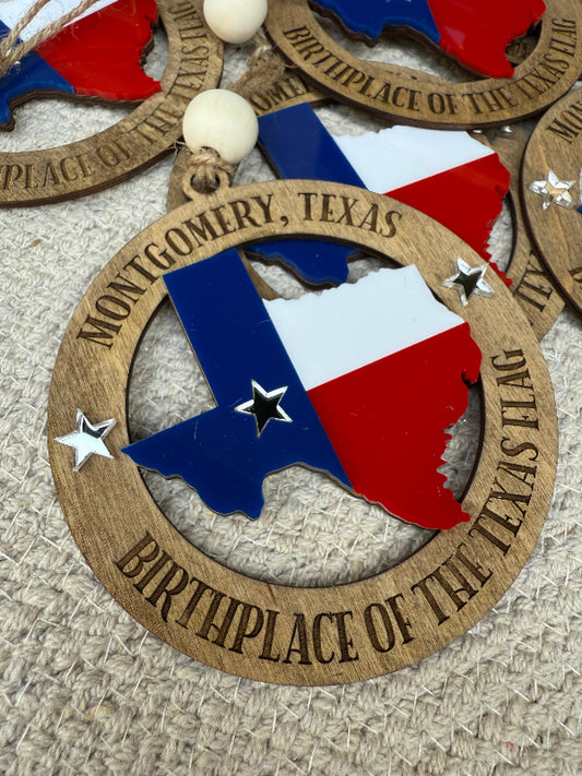 Wooden ornament with Texas flag design and 'Montgomery, Texas' text on a textured surface.