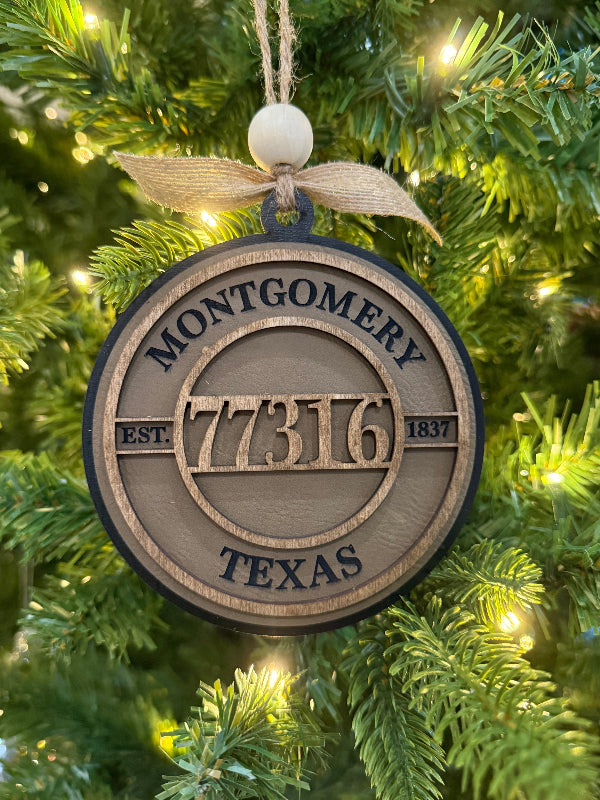 Decorative ornament with 'Montgomery 77316 Texas' on a Christmas tree.
